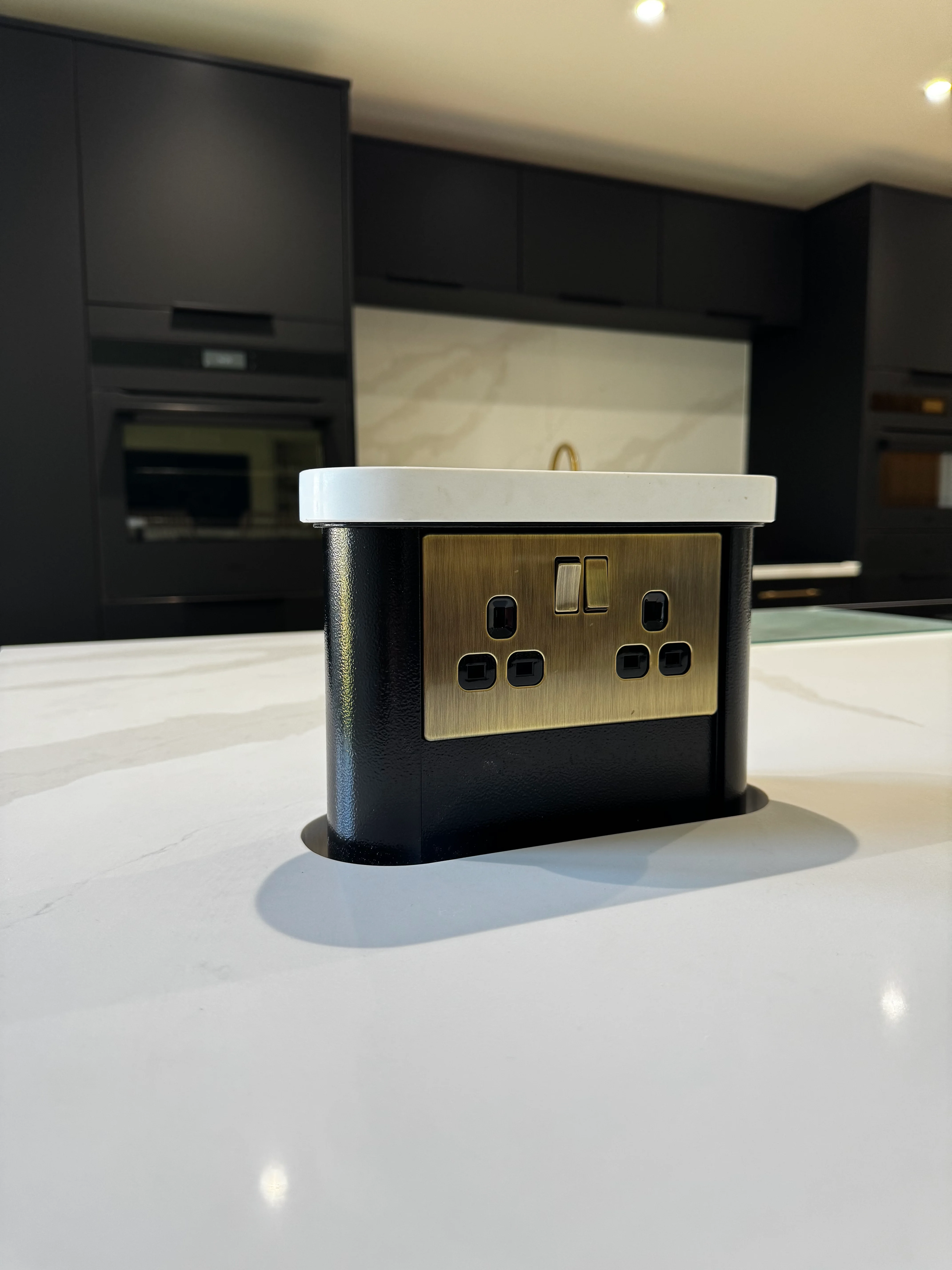 High-end kitchen rewire — brass pop-up socket in quartz island